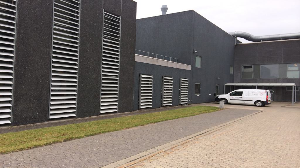 Drejbare aluminiumslameller foran høje vinduespartier på en virksomhed i Hedensted