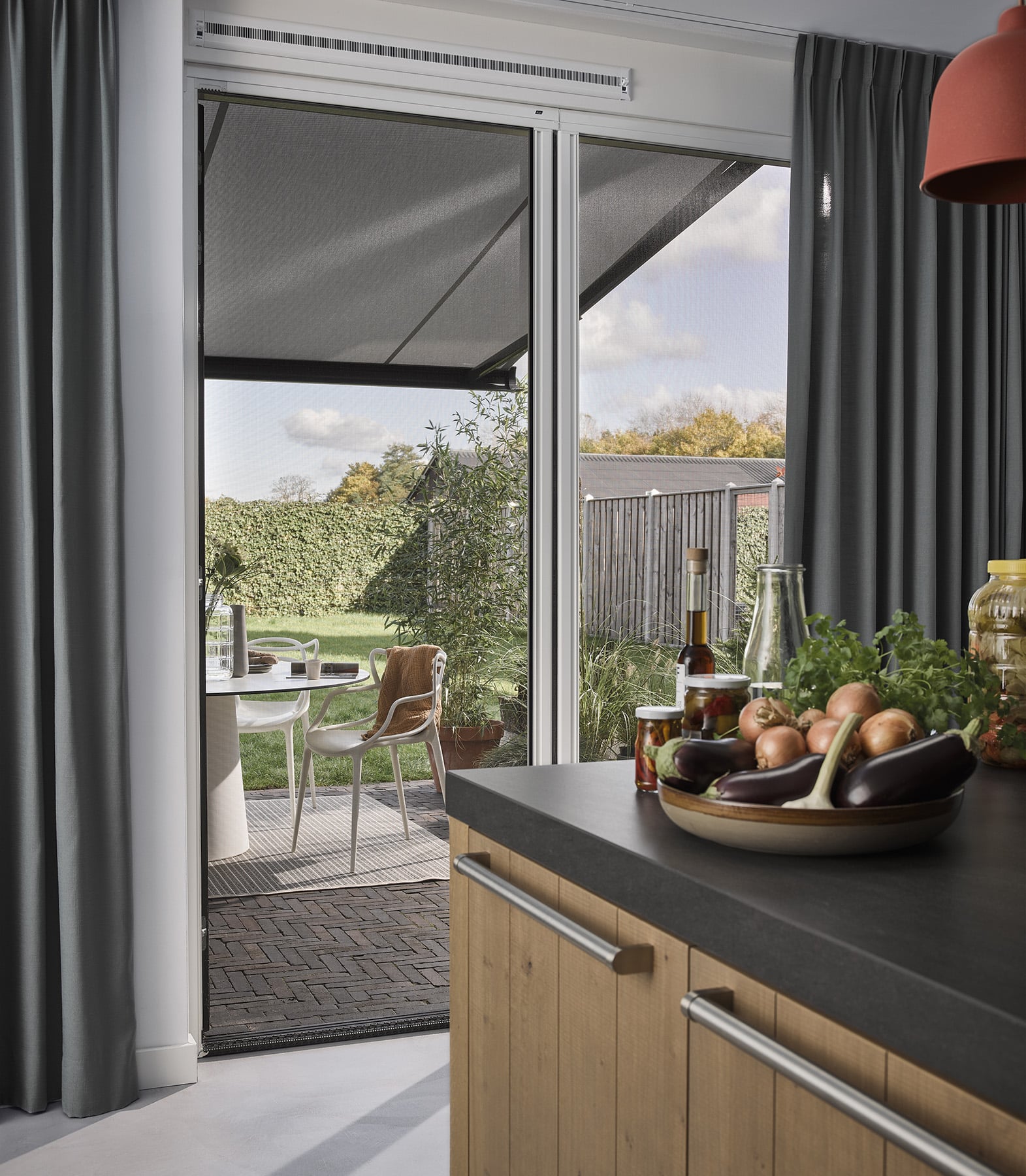 Terrasse med udfoldet markise, der skaber skygge ved boligen