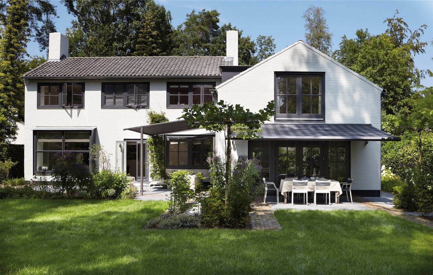 Markiser monteret på et stort lyst hus med terrasse og have