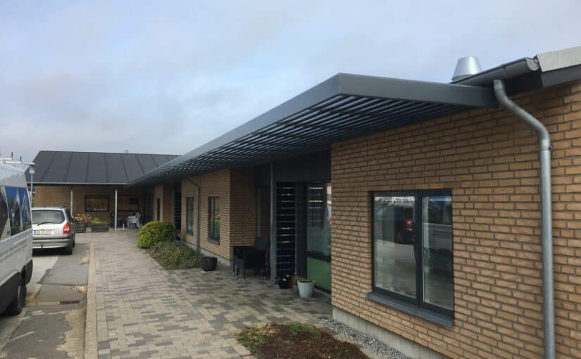 Lamelafskærmning med c-lameller monteret over vinduer på murstensbygning