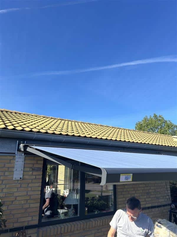 Nova Hüppe Prima C1 markise med blåstribet dug og mørkt stel over terrasse i Sønderborg
