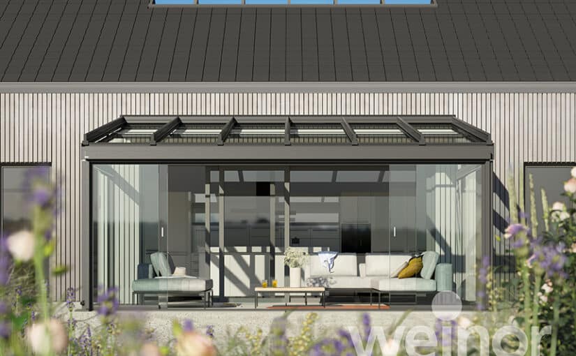 Weinor Terrazza Sempra terrasseoverdækning monteret op af en træfacade med blomster i forgrunden