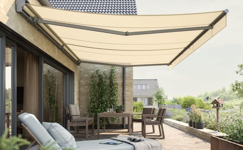 Weinor Topas II markise monteret på murstensvæg over terrasse med grønne planter i baggrunden