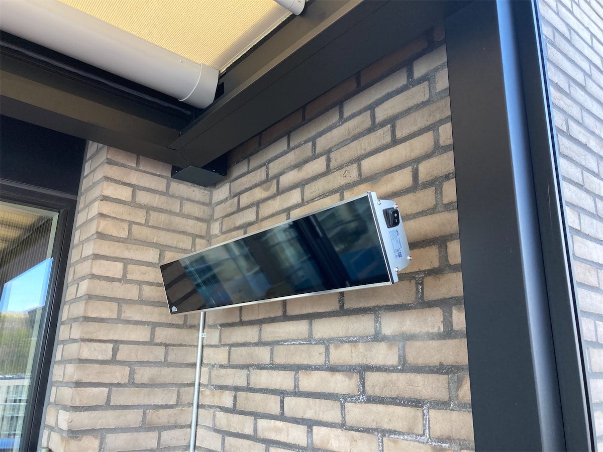Slukket Frico Relax Glass io terrassevarmer med mørk glasfront monteret på en mur i Vejle