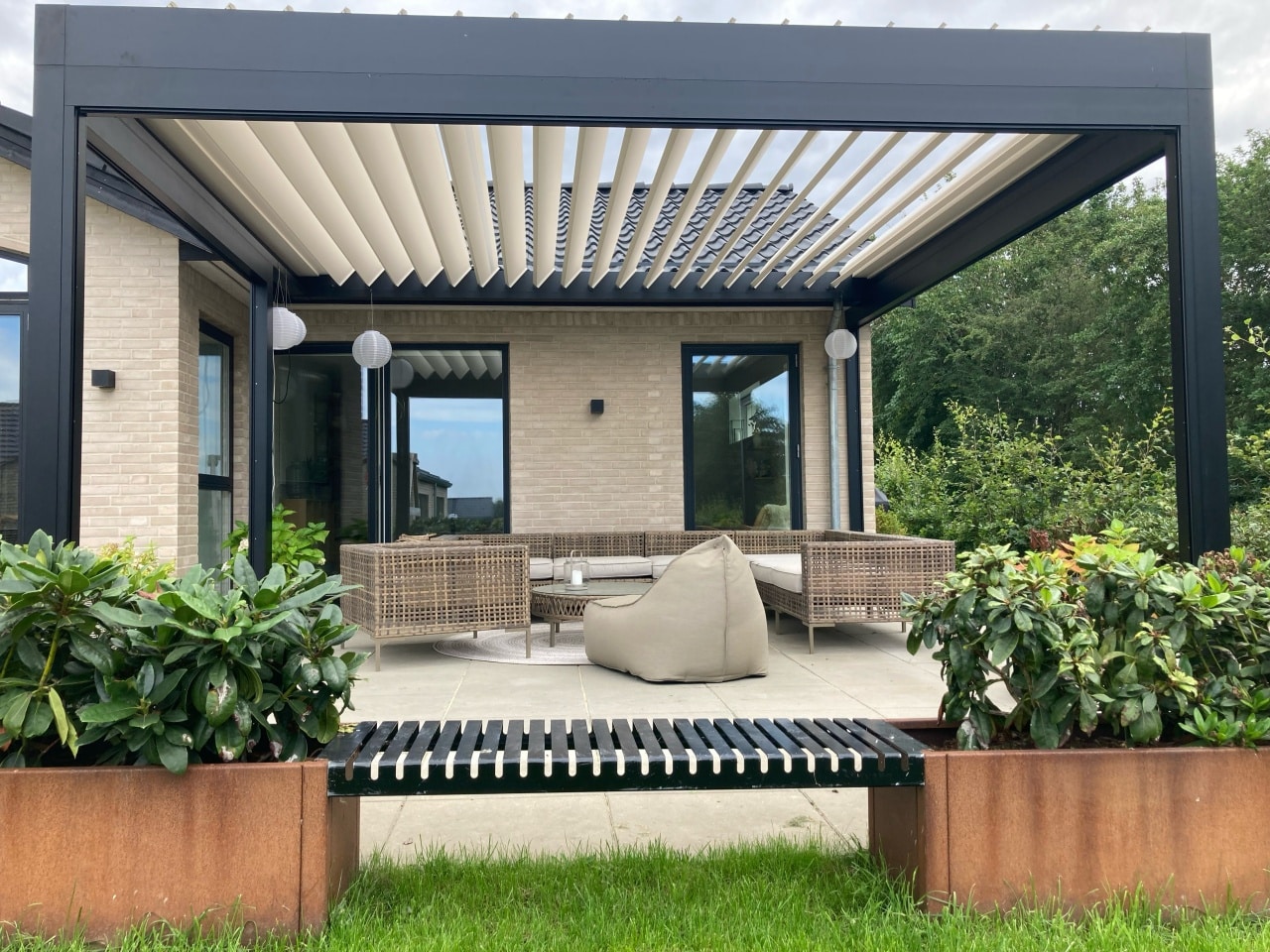 Pergola med lameltag over indrettet terrasse ved dansk hjem