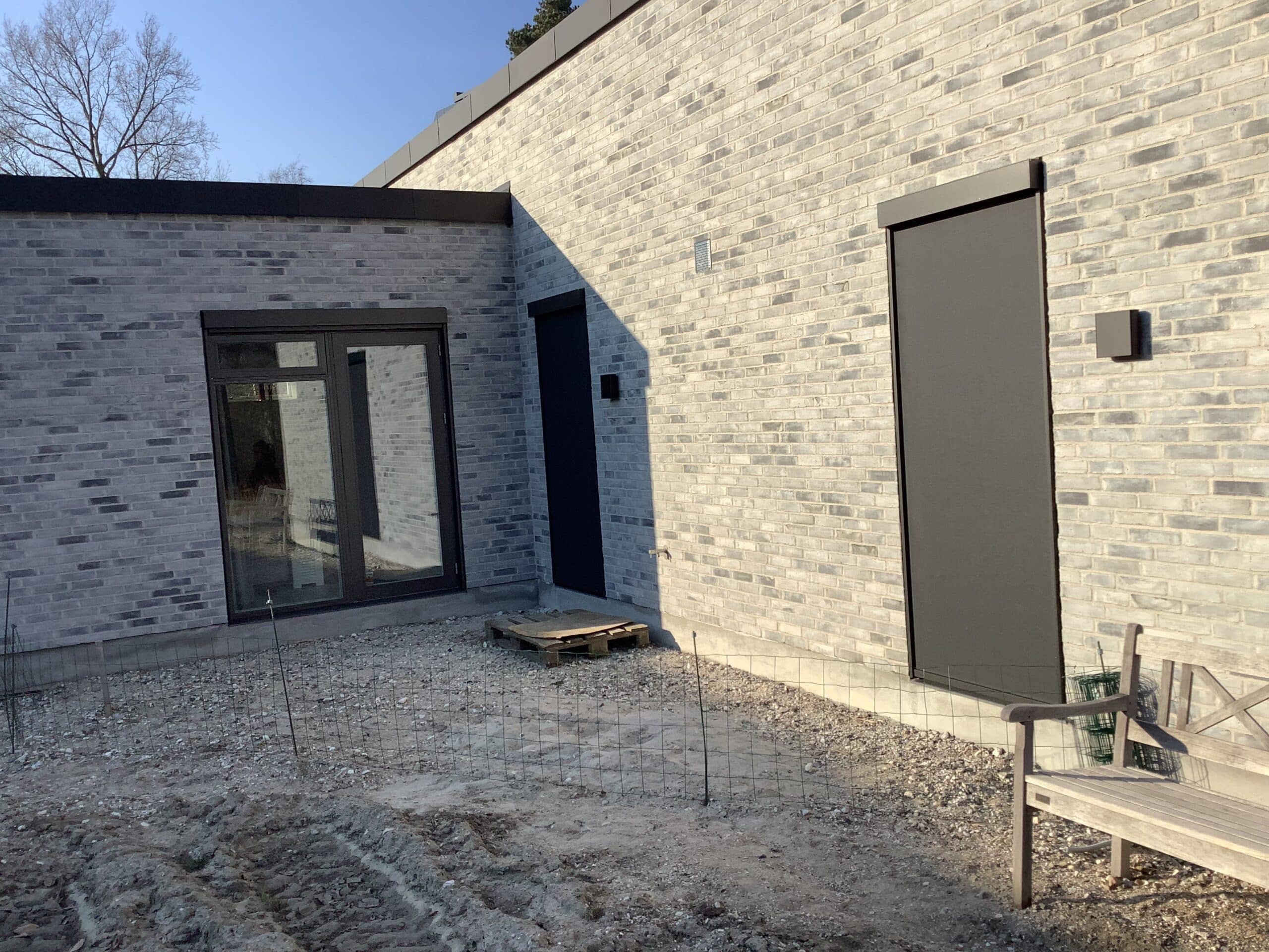 Nybygget murstenshus med en Renson Fixscreen Minimal sænket foran et smalt vinduesparti