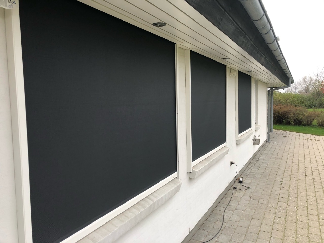 Udvendige screens monteret på flere vinduer på eksisterende hus