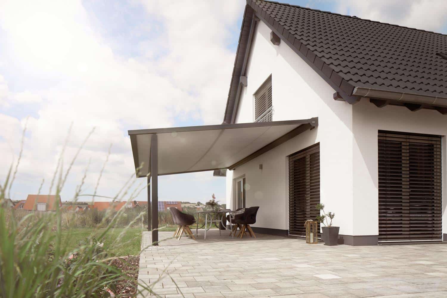 Perea P60 med lys dug over en terrasse ved et hvidt hus med saddeltag