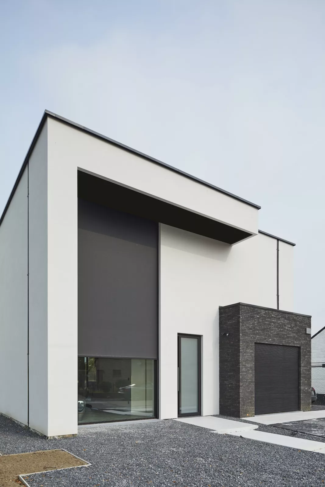 Høj Wilms screen delvist sænket foran et stort glasparti på et moderne hus