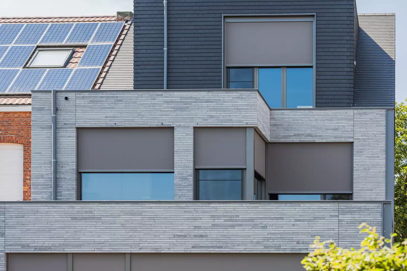 Wilms ZipX Zero – screens på hus i to etager Hus i to etager med lys murstensfacade, mørk beklædning og indbyggede screens delvist sænket